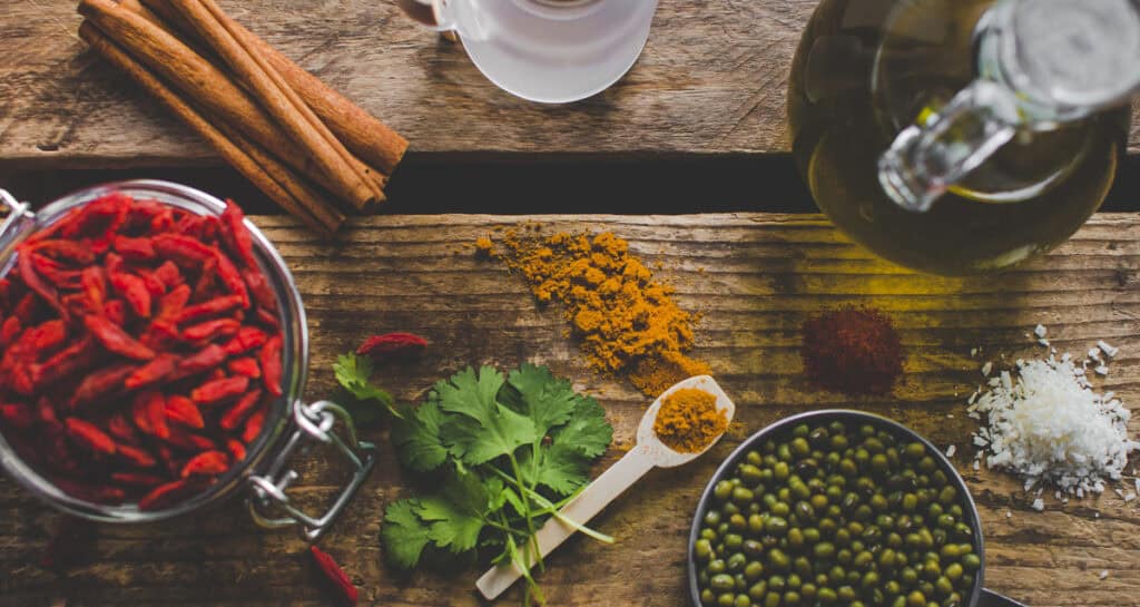 A table of whole food ingredients used in holistic nutrition, including mung beans, goji berries, turmeric, cinnamon stick herbs and oil.