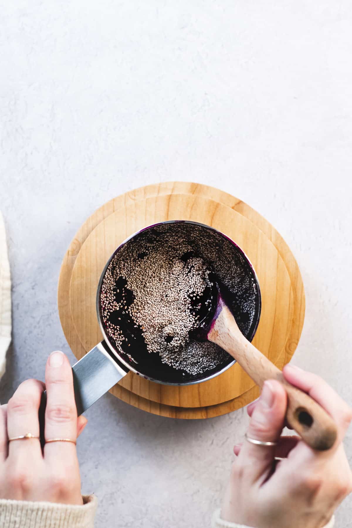 Chia seeds being stirred into a pot of simmered blueberries.