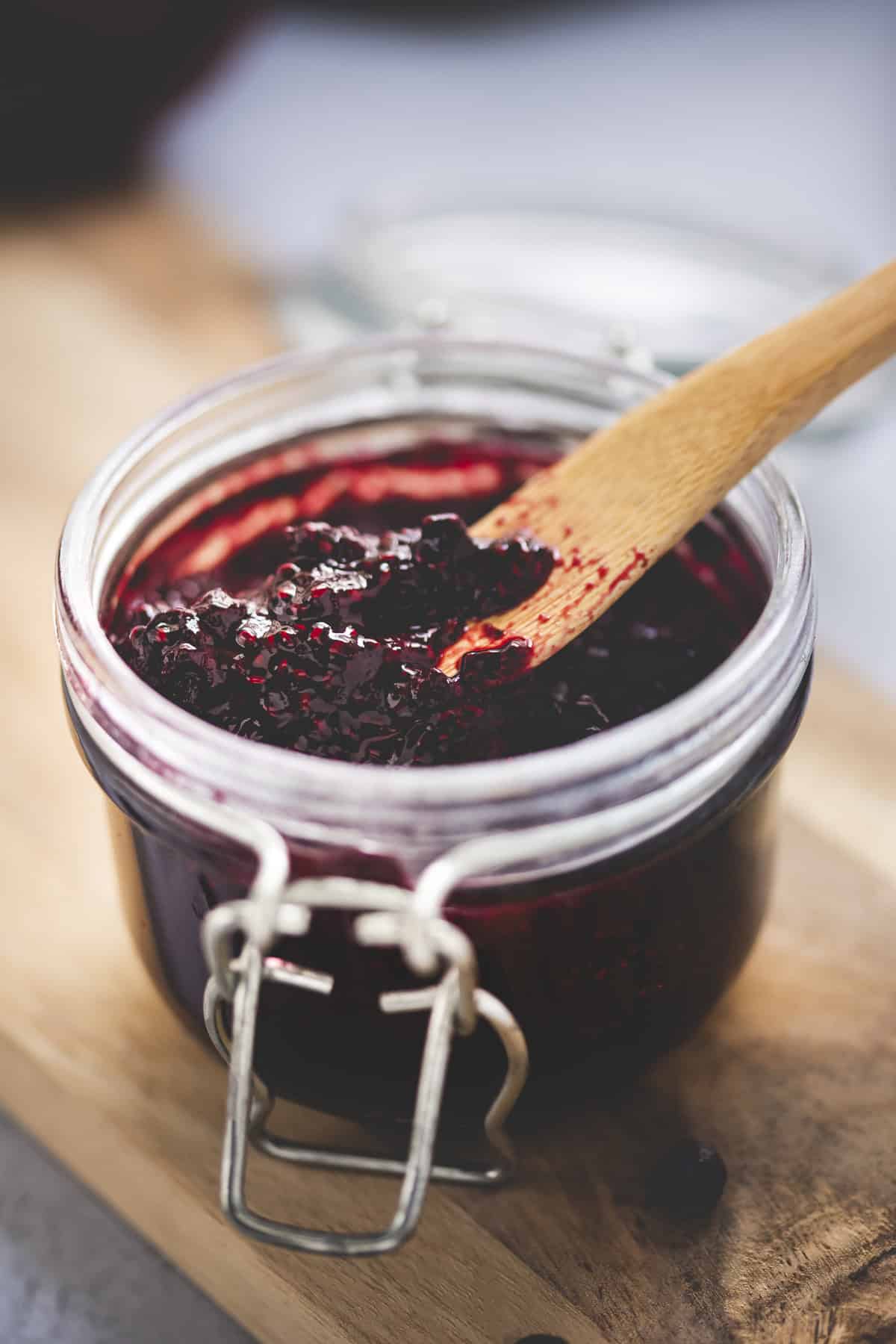 A wooden butterknife dipped into chia-thickened blueberry jam.