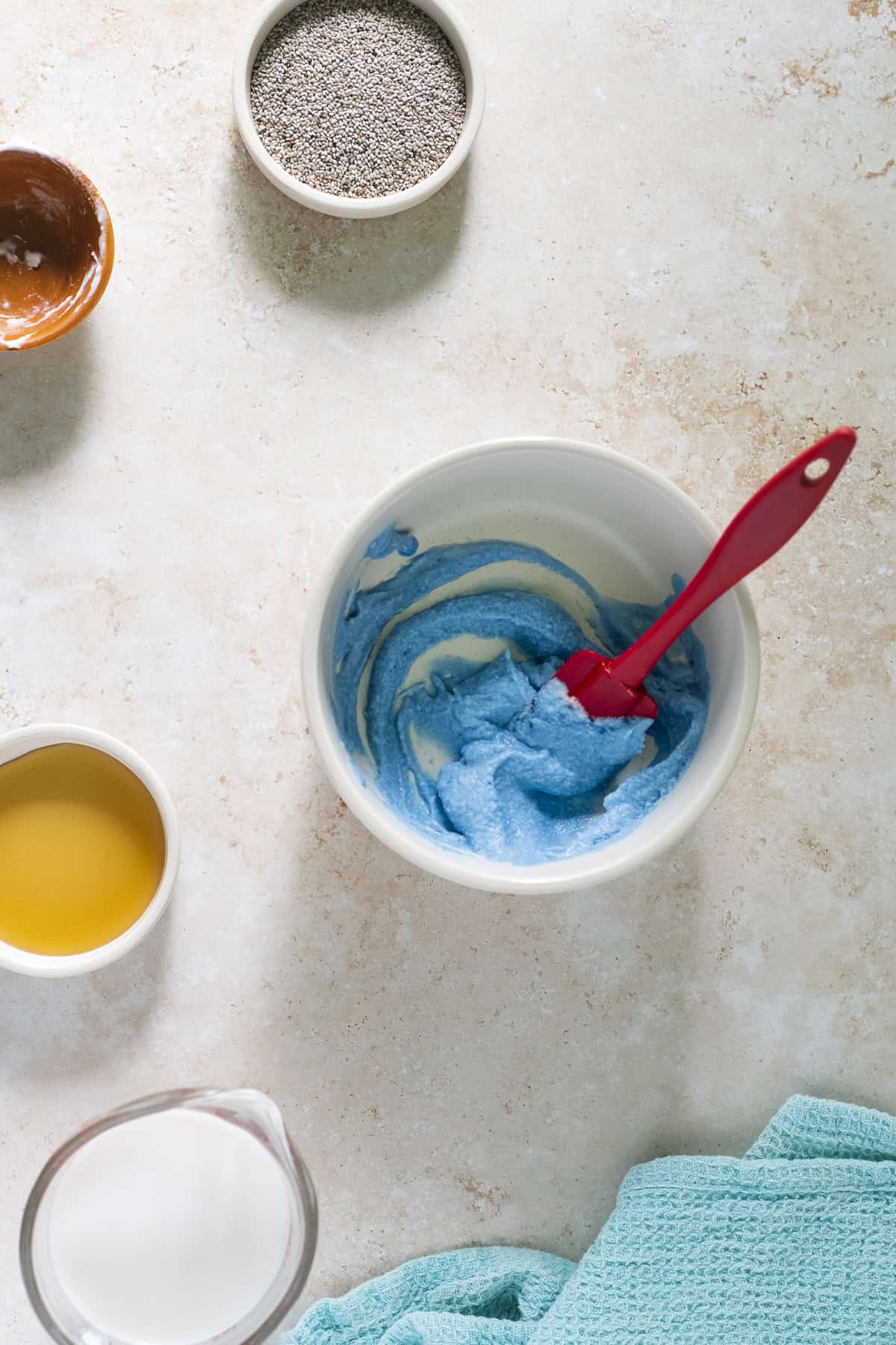 Coconut cream and blue-green algae freshly mixed with a red spatula.