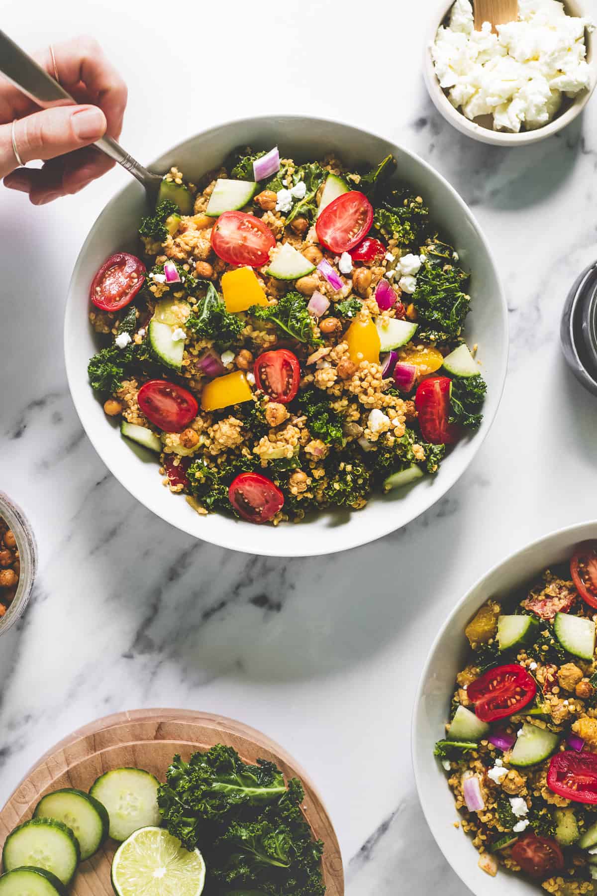 A heaping bowl of fresh quinoa salad with kale and chickpeas being dug into with a fork.