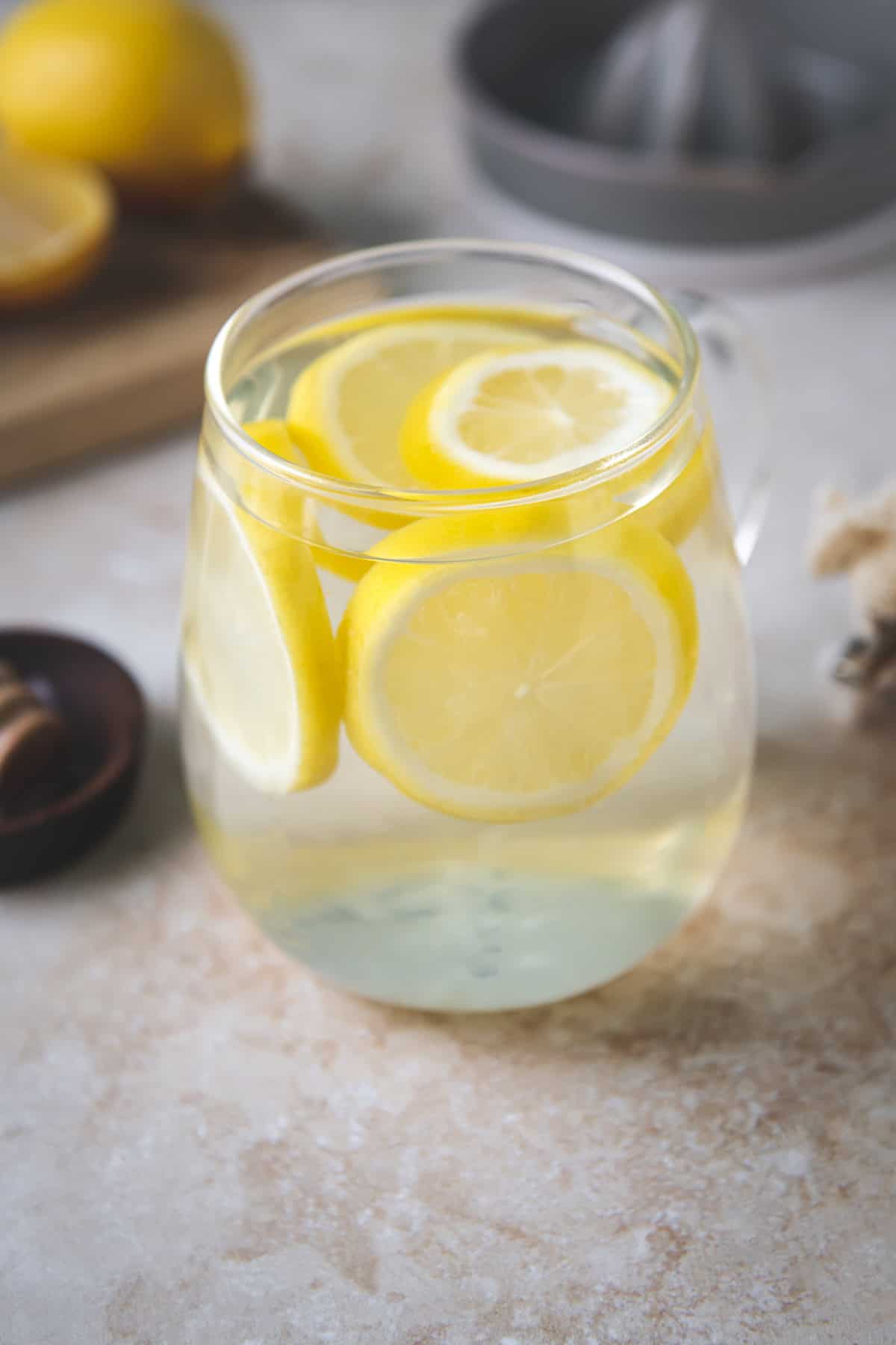 A glass mug filled with water and floating lemon rounds.